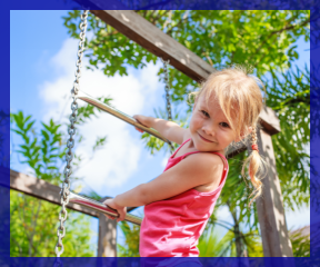 Little girl hangs off playground ladder