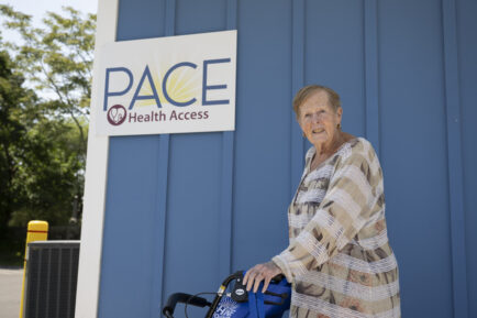 A senior woman poses outside a food pantry called PACE 